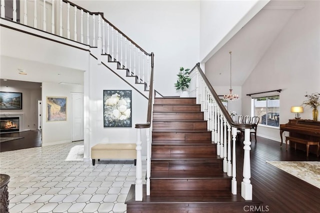 13440 Pala Ave, Sylmar, CA 91342 - stairway featuring a towering ceiling, baseboards, a chandelier, and a glass covered fireplace