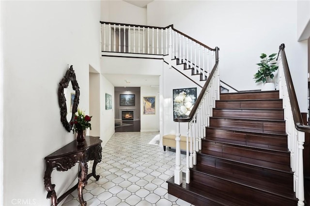 13440 Pala Ave, Sylmar, CA 91342 - staircase featuring a towering ceiling, a warm lit fireplace, tile patterned floors, and baseboards