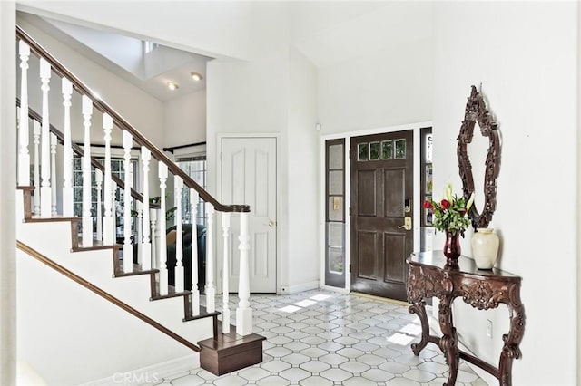 entryway featuring baseboards, a high ceiling, stairs, and tile patterned floors