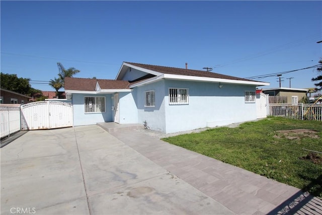 view of front of property with a front yard, fence, a gate, and stucco siding