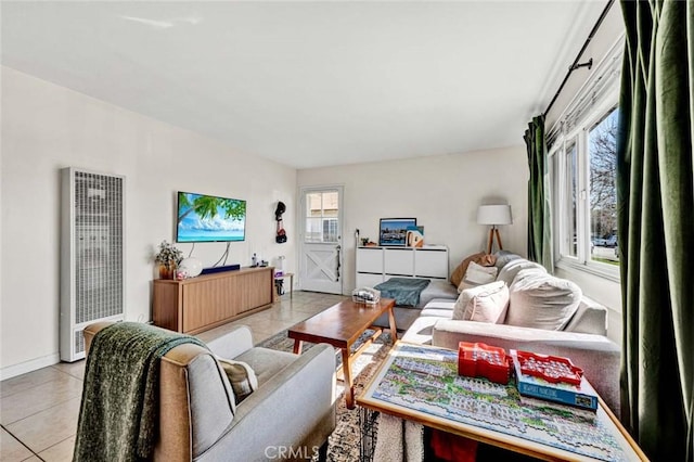 living area featuring a heating unit, baseboards, and light tile patterned flooring