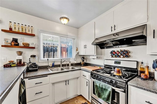 kitchen with dark countertops, gas stove, white cabinets, a sink, and under cabinet range hood