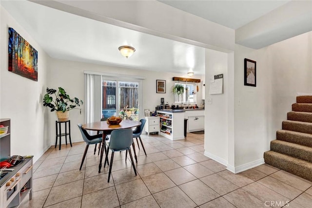 dining area with light tile patterned floors, baseboards, and stairway