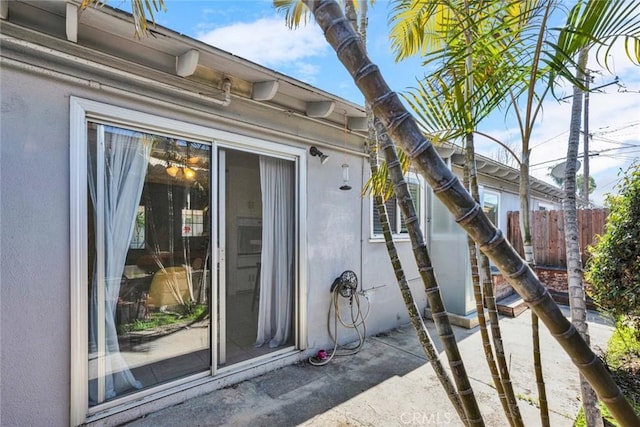 doorway to property featuring fence, a patio, and stucco siding