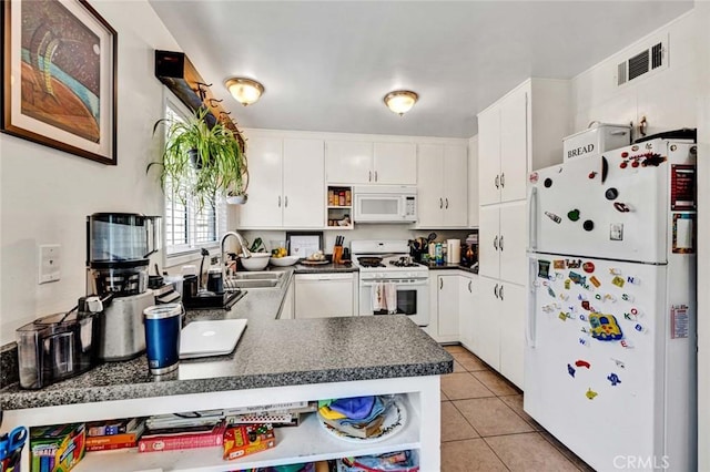 kitchen featuring white appliances, visible vents, white cabinets, dark countertops, and a sink