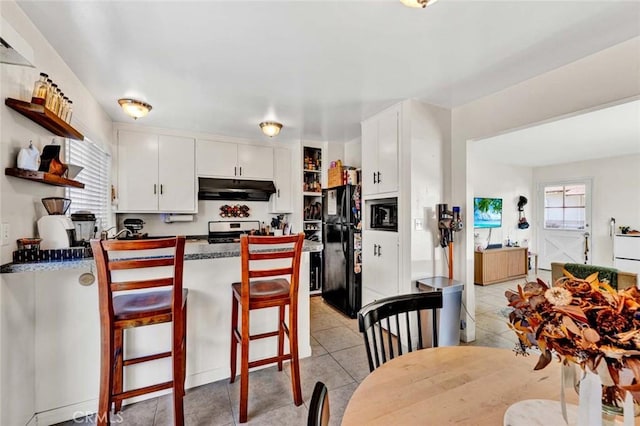 kitchen with freestanding refrigerator, stainless steel stove, white cabinets, and under cabinet range hood