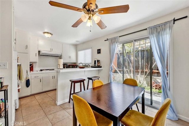 dining room featuring light tile patterned flooring, a ceiling fan, and baseboards