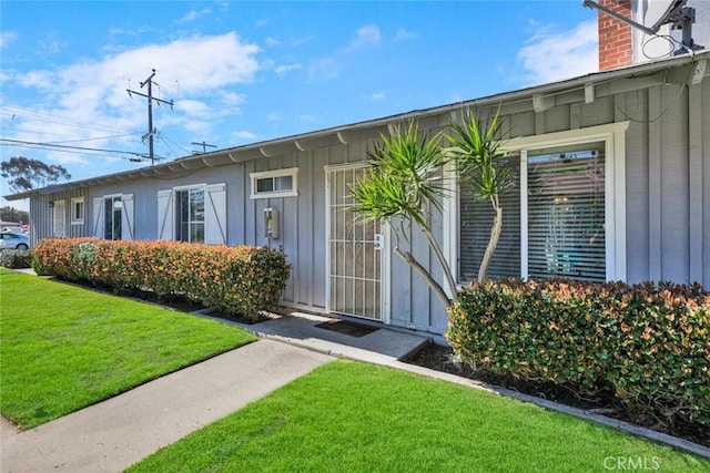 view of exterior entry with a yard and board and batten siding