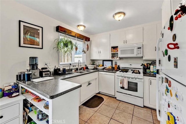 kitchen with dark countertops, white appliances, white cabinetry, and a sink