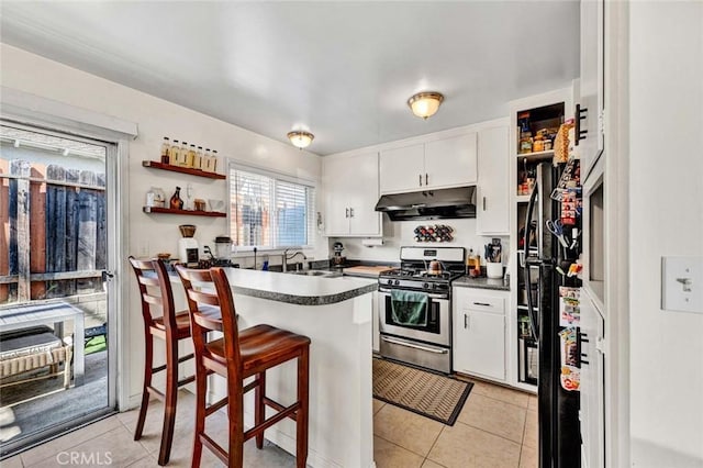 kitchen featuring open shelves, stainless steel gas range, dark countertops, and under cabinet range hood