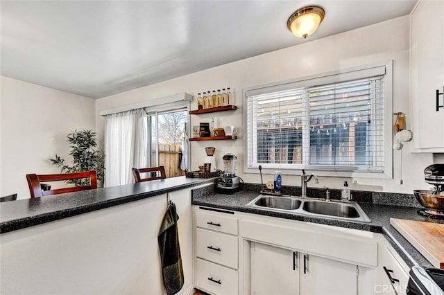 kitchen featuring dark countertops, white cabinets, and a sink