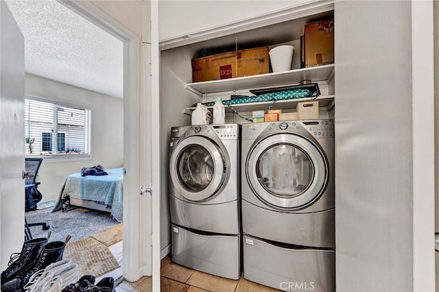 laundry area with laundry area, light tile patterned floors, a textured ceiling, and independent washer and dryer