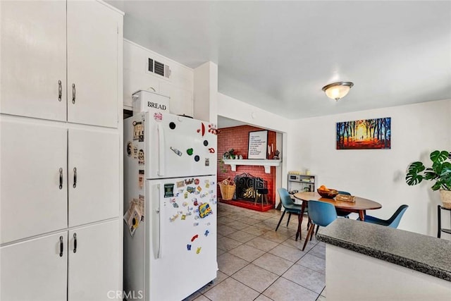 kitchen featuring light tile patterned flooring, visible vents, white cabinetry, freestanding refrigerator, and dark countertops