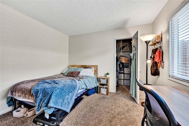 carpeted bedroom with a textured ceiling, a spacious closet, a closet, and baseboards