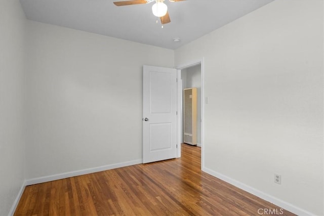 spare room with a ceiling fan, baseboards, and wood finished floors