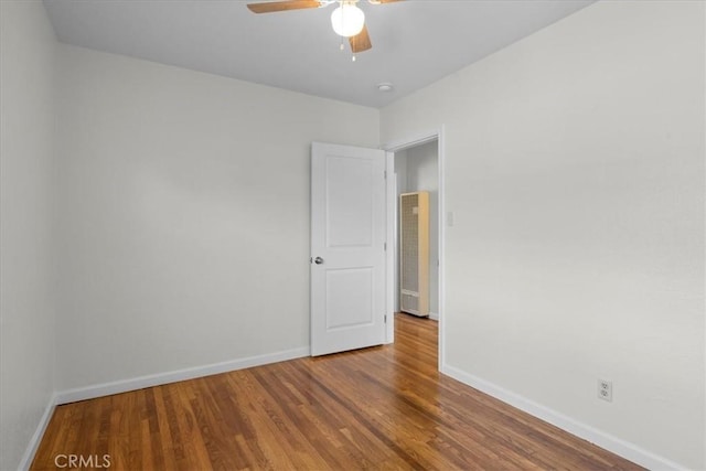 empty room featuring baseboards, ceiling fan, and wood finished floors