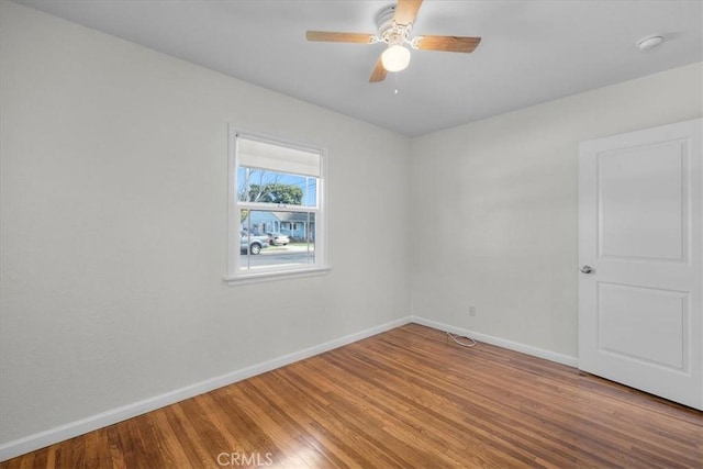 empty room with ceiling fan, wood finished floors, and baseboards