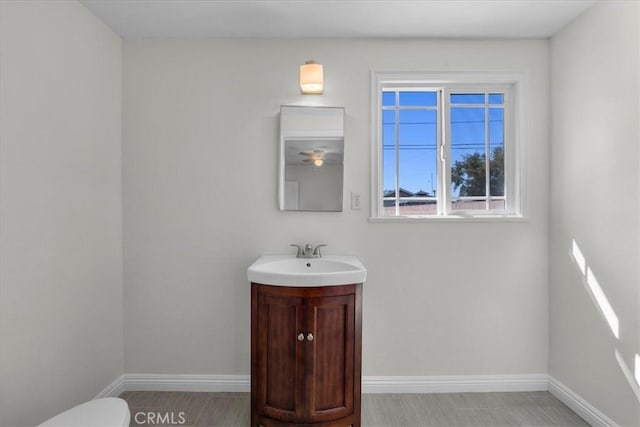 bathroom with toilet, vanity, and baseboards