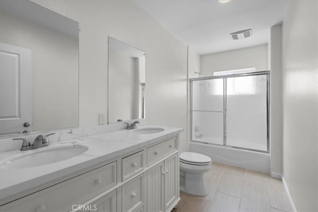 bathroom with enclosed tub / shower combo, visible vents, a sink, and toilet