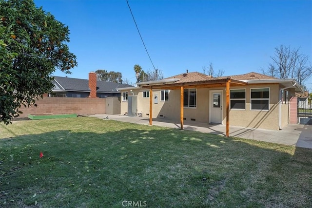 back of property featuring fence, a yard, crawl space, stucco siding, and a patio area