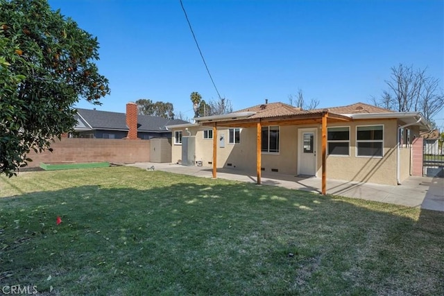 rear view of property featuring a patio area, stucco siding, fence, and a lawn