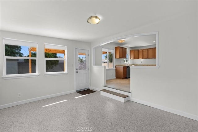 foyer entrance with arched walkways, baseboards, and plenty of natural light
