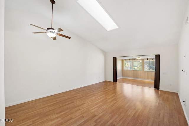 unfurnished living room with a skylight, baseboards, ceiling fan, light wood-style floors, and high vaulted ceiling