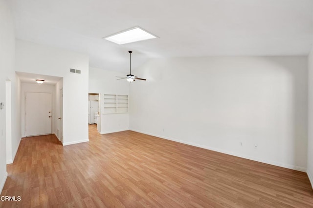 unfurnished living room with ceiling fan, visible vents, baseboards, light wood finished floors, and lofted ceiling with skylight