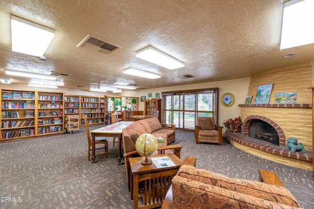 living area featuring a brick fireplace, carpet, visible vents, and a textured ceiling