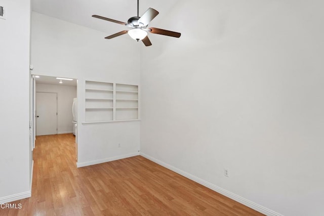 empty room featuring ceiling fan, light wood finished floors, and baseboards