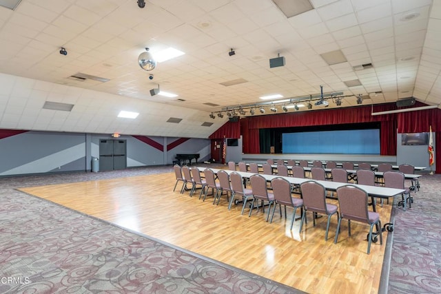 cinema with lofted ceiling, rail lighting, and wood finished floors