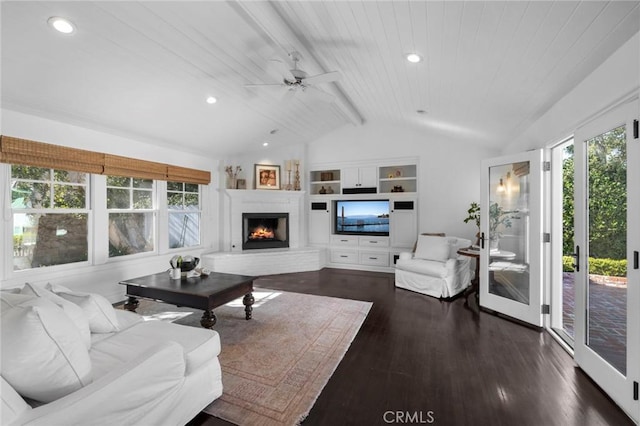 living area with dark wood-style floors, a warm lit fireplace, plenty of natural light, and lofted ceiling with beams