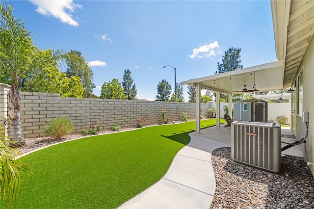 view of yard featuring a patio, a fenced backyard, a storage shed, central AC, and an outdoor structure