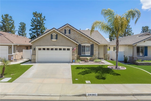 view of front of property featuring concrete driveway, fence, a garage, stone siding, and a front lawn