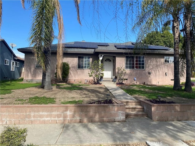 ranch-style home with solar panels and stucco siding