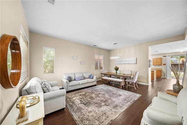 living area featuring dark wood-style flooring, visible vents, and baseboards