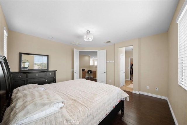 bedroom featuring dark wood-type flooring, multiple windows, visible vents, and baseboards