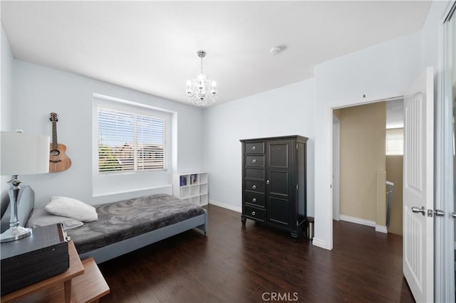 bedroom with a chandelier, dark wood-type flooring, and baseboards