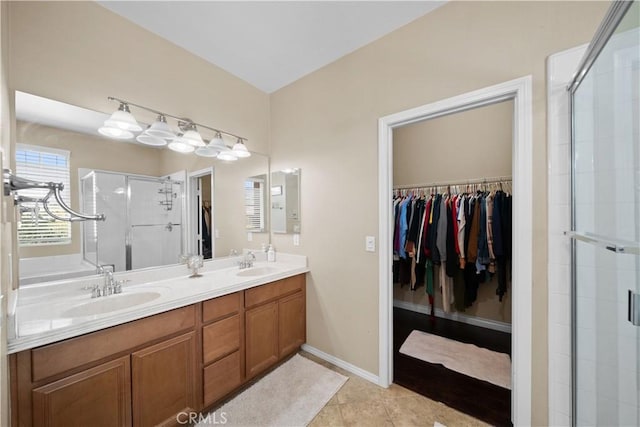 full bathroom featuring a sink, a stall shower, and a walk in closet