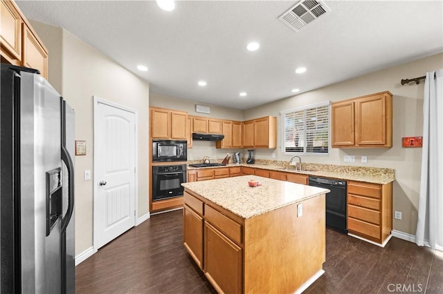 kitchen with under cabinet range hood, visible vents, a center island, black appliances, and dark wood finished floors