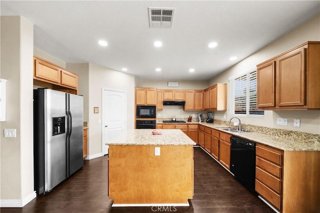 kitchen featuring light stone counters, a sink, visible vents, a center island, and black appliances