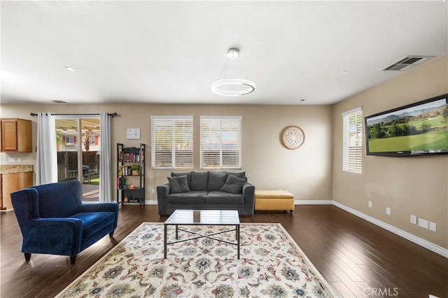 living room with baseboards, dark wood finished floors, visible vents, and a healthy amount of sunlight