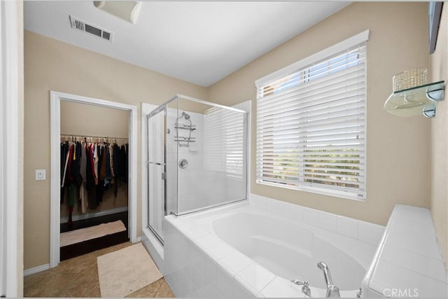 full bath with a walk in closet, a garden tub, visible vents, a shower stall, and tile patterned floors