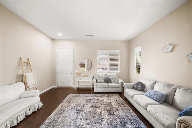 living area with dark wood-type flooring, visible vents, and baseboards