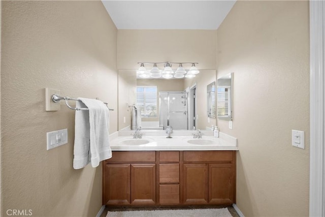 bathroom with a sink, a shower stall, and double vanity