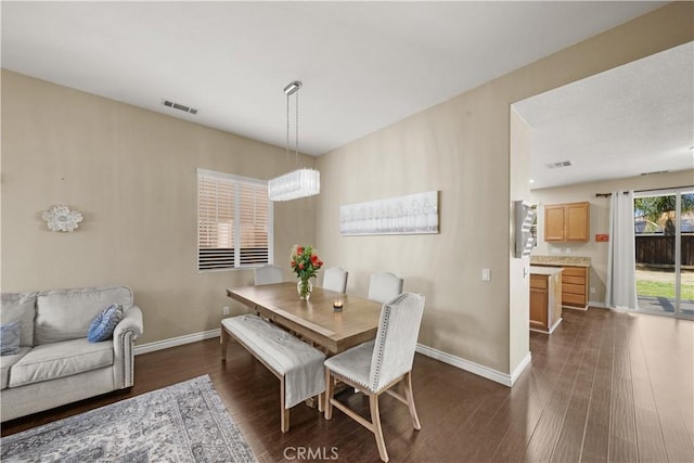 dining space featuring dark wood-type flooring, visible vents, and baseboards