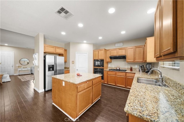 kitchen with visible vents, a sink, a kitchen island, under cabinet range hood, and black appliances