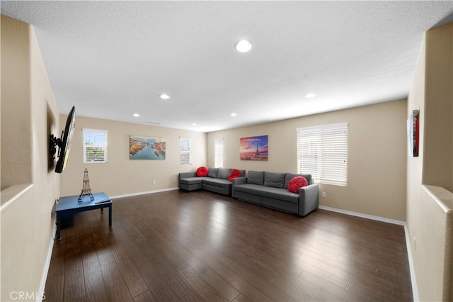 living room featuring dark wood-type flooring, a healthy amount of sunlight, and baseboards