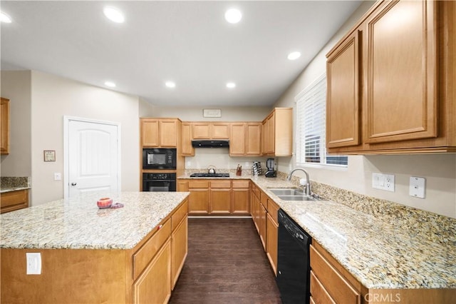 kitchen featuring black appliances, a kitchen island, a sink, and light stone countertops