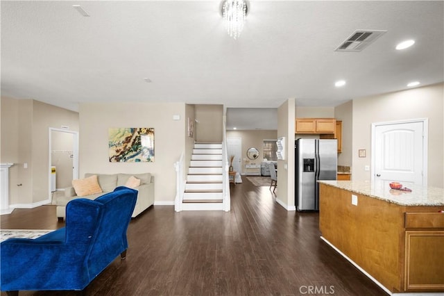 interior space with visible vents, dark wood finished floors, open floor plan, a center island, and stainless steel refrigerator with ice dispenser